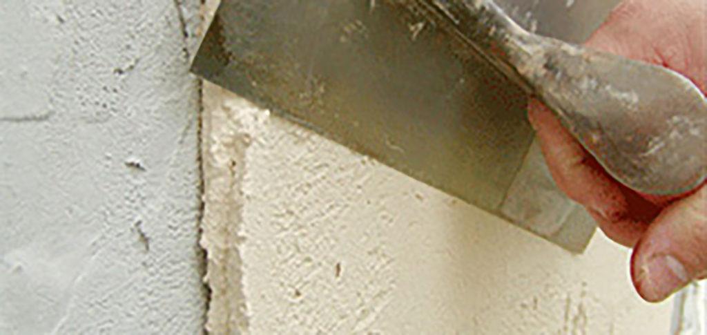 Hand with trowel applying stucco